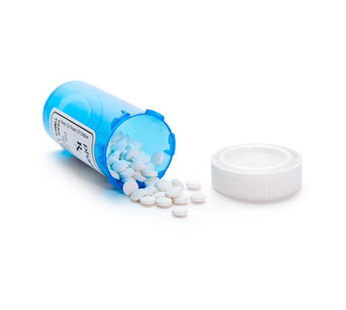 A blue pill bottle with pills spilling out on a white background.