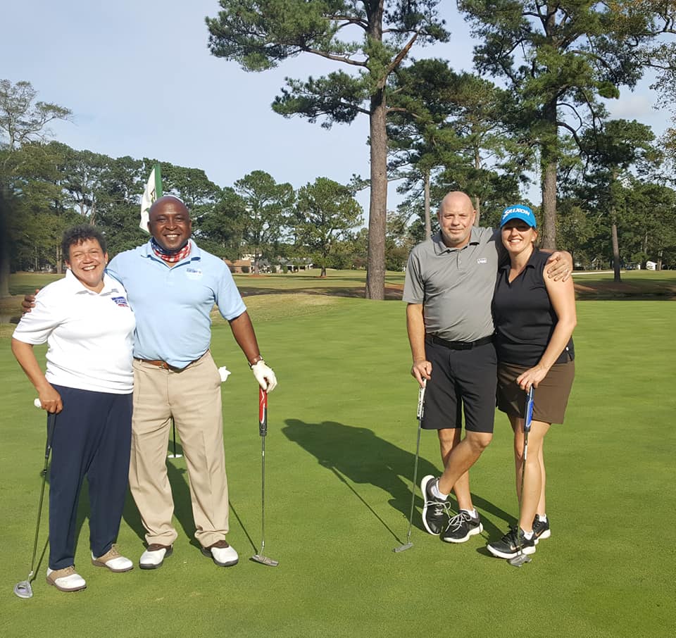 Couples posing for a picture with golf sticks